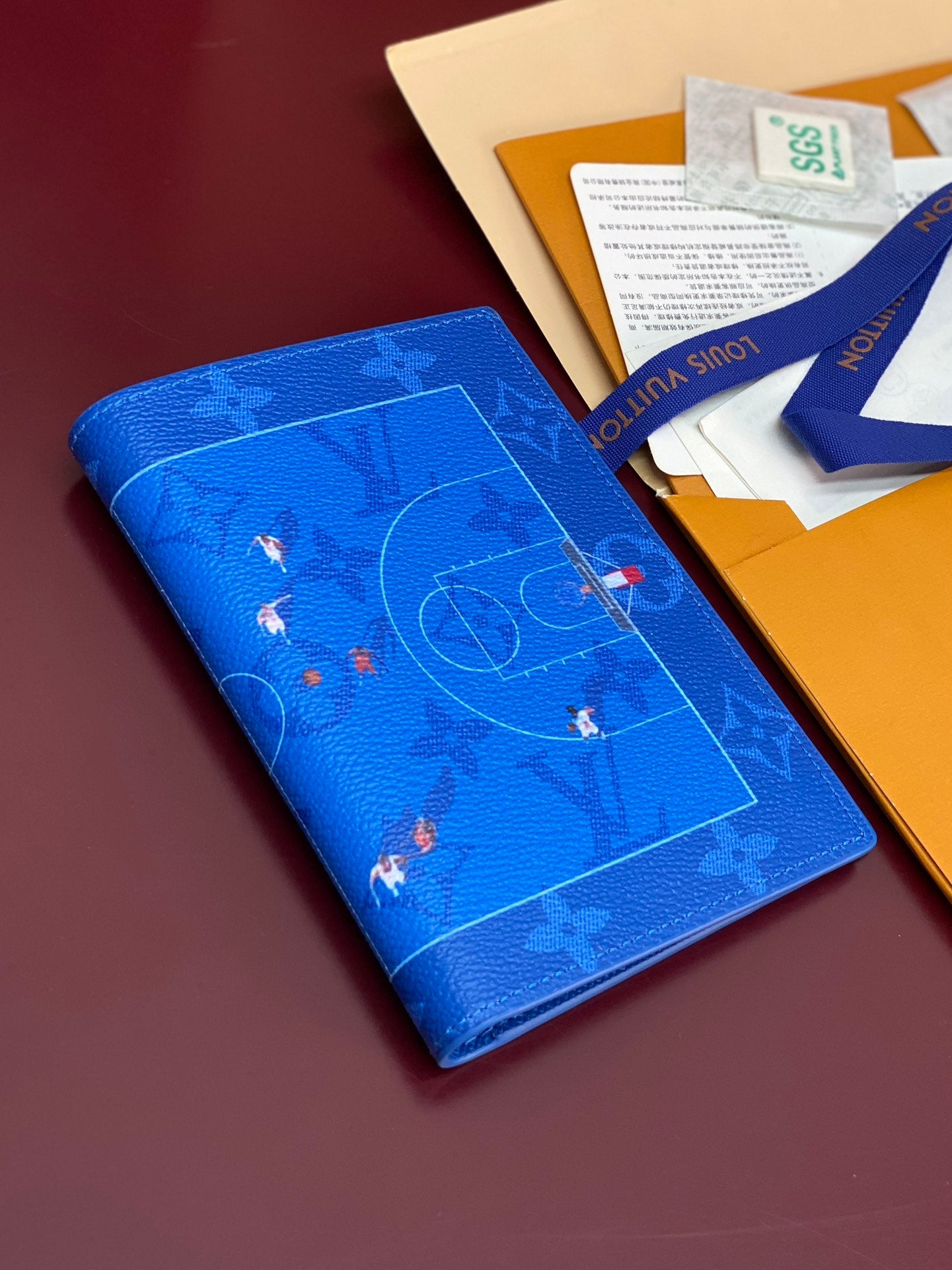 Blue small bag with monogram print and front flap, held in box