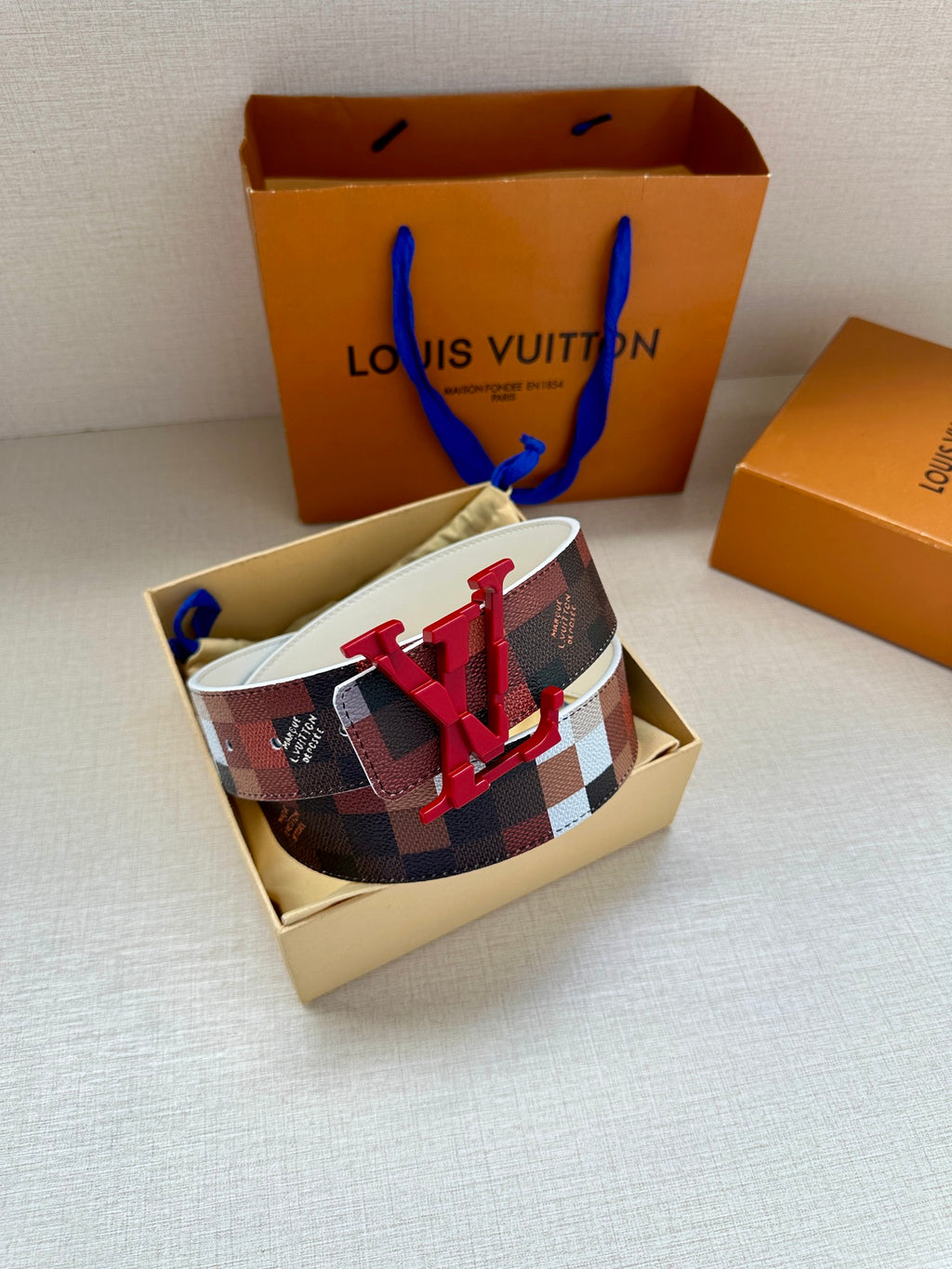 Louis Vuitton checkered belt with red V buckle and white strap, side view