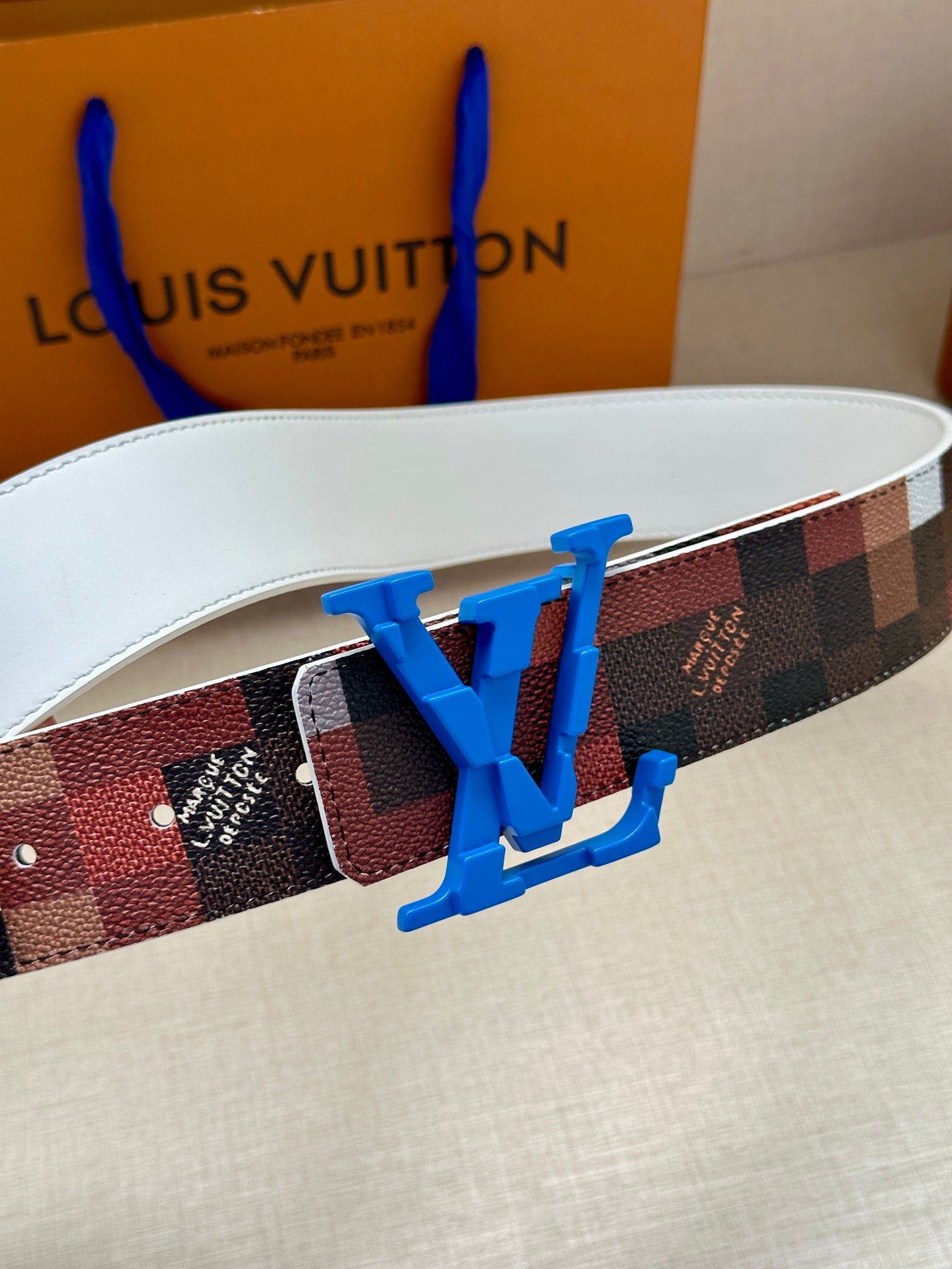 Louis Vuitton belt close-up: checkered strap with blue LV buckle