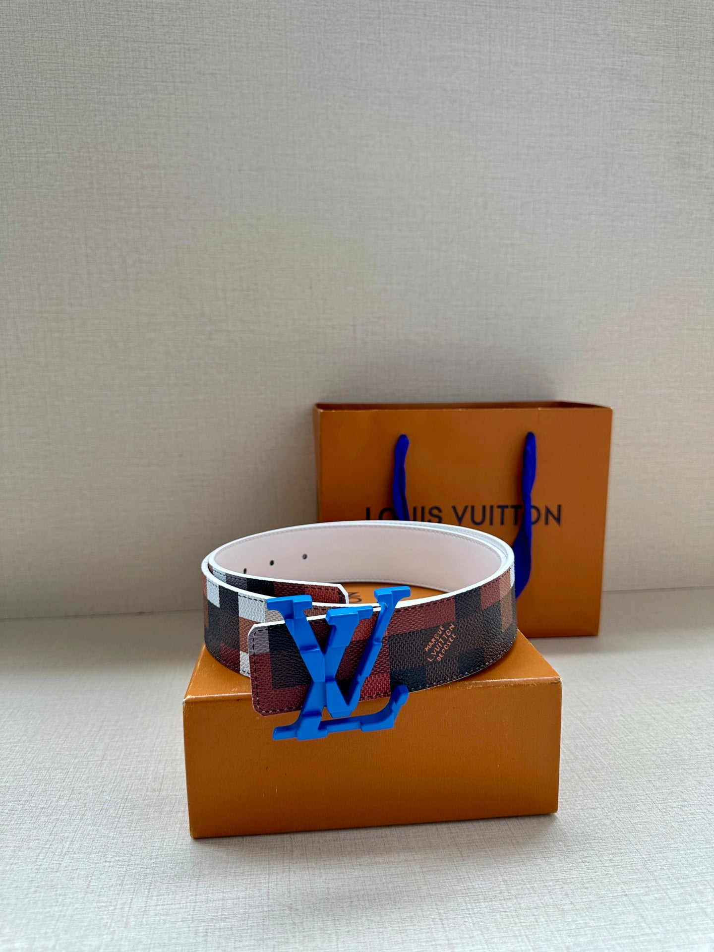 Louis Vuitton belt with dark checkered strap, blue LV buckle, and white leather edge