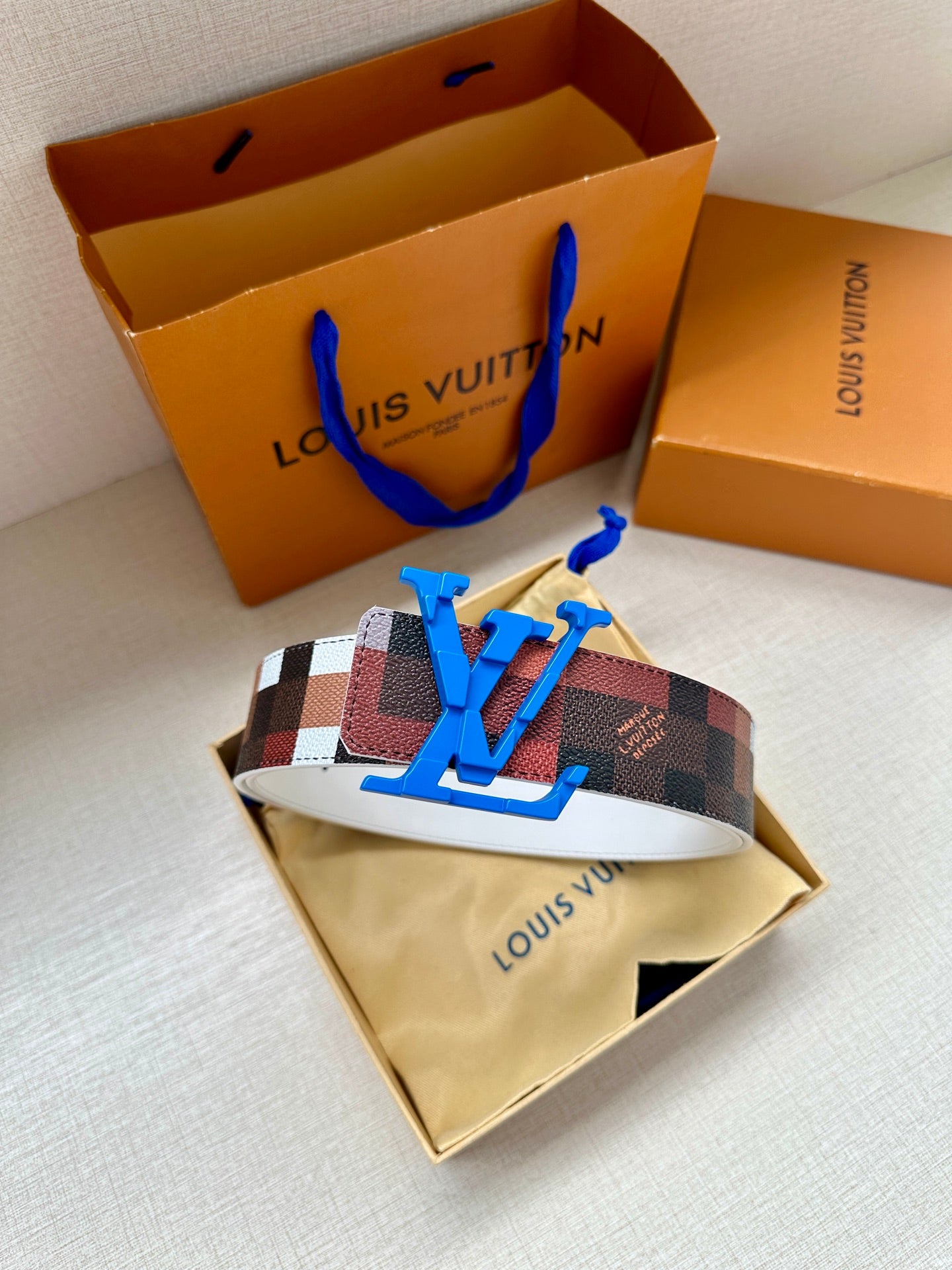 Louis Vuitton belt with checkered strap and blue LV buckle on white lining