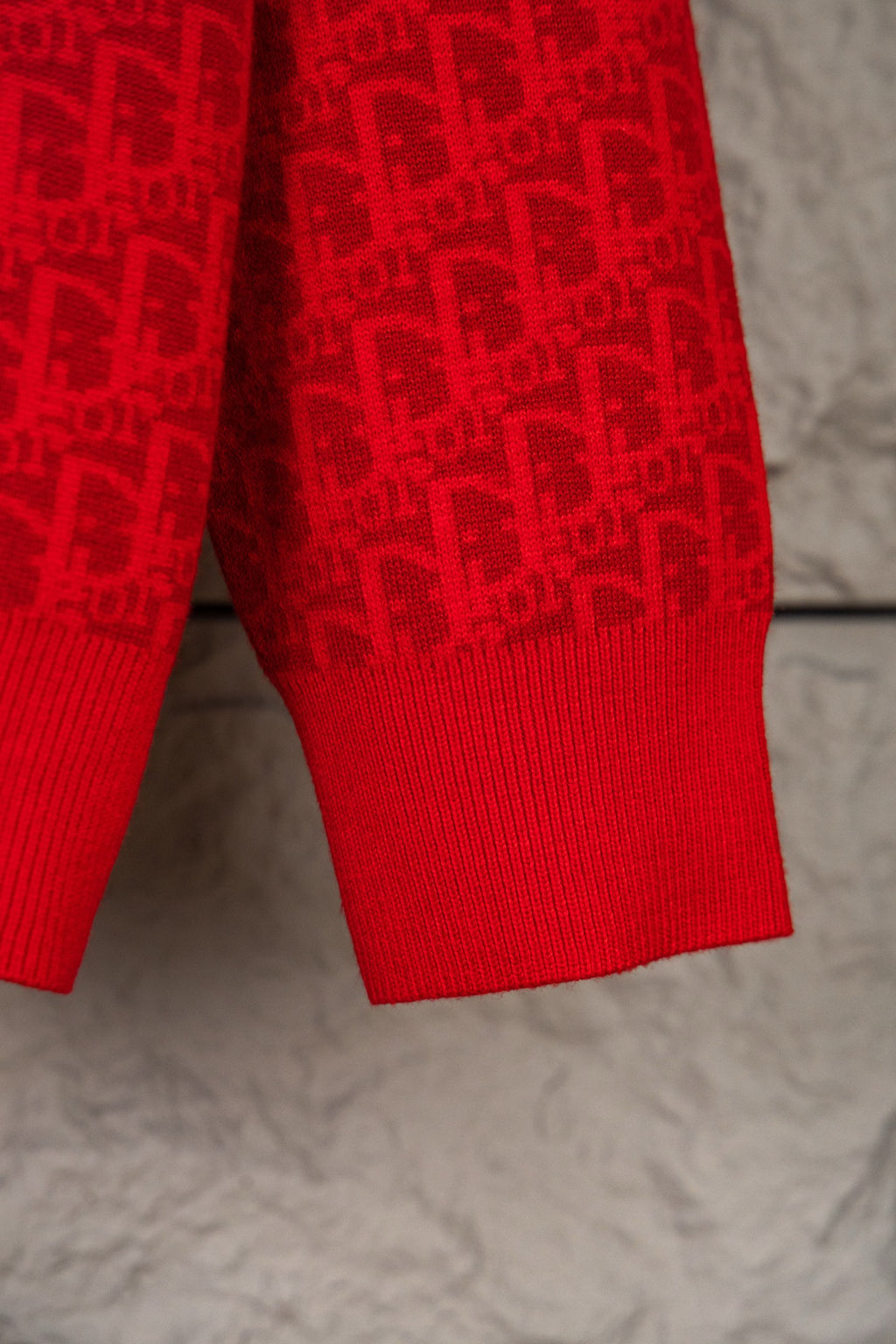Red knit hoodie lower torso with ribbed hem and allover logo pattern