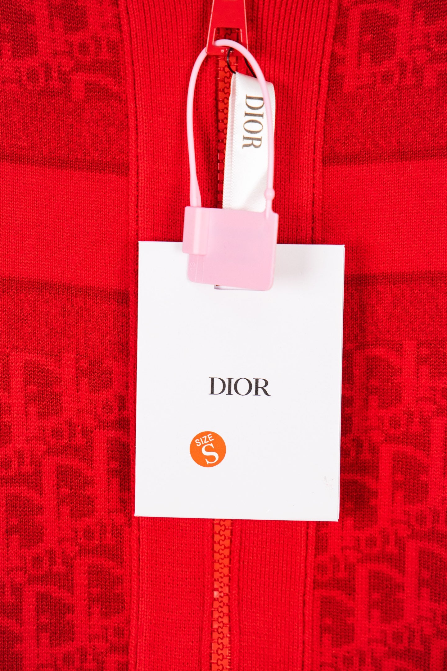 Red zip hoodie with white retail tag reading DIOR