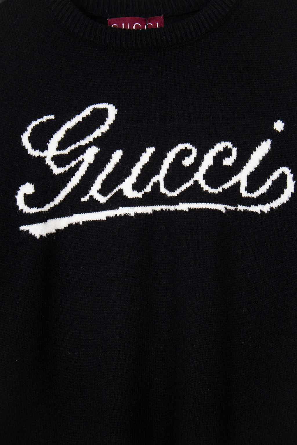 Black knit sweater with large white Gucci script graphic