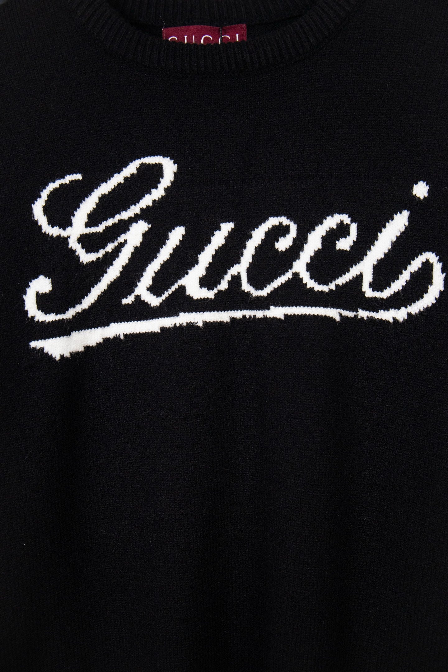 Black knit sweater with large white Gucci script graphic