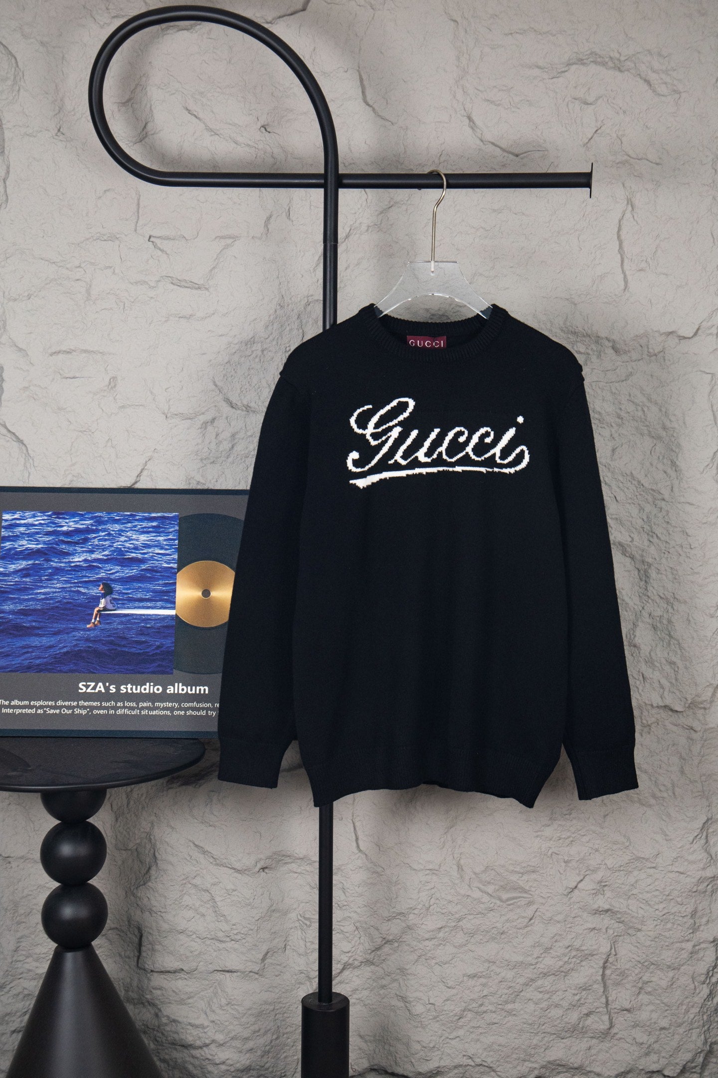 Black long-sleeve sweater on hanger with white Gucci script logo