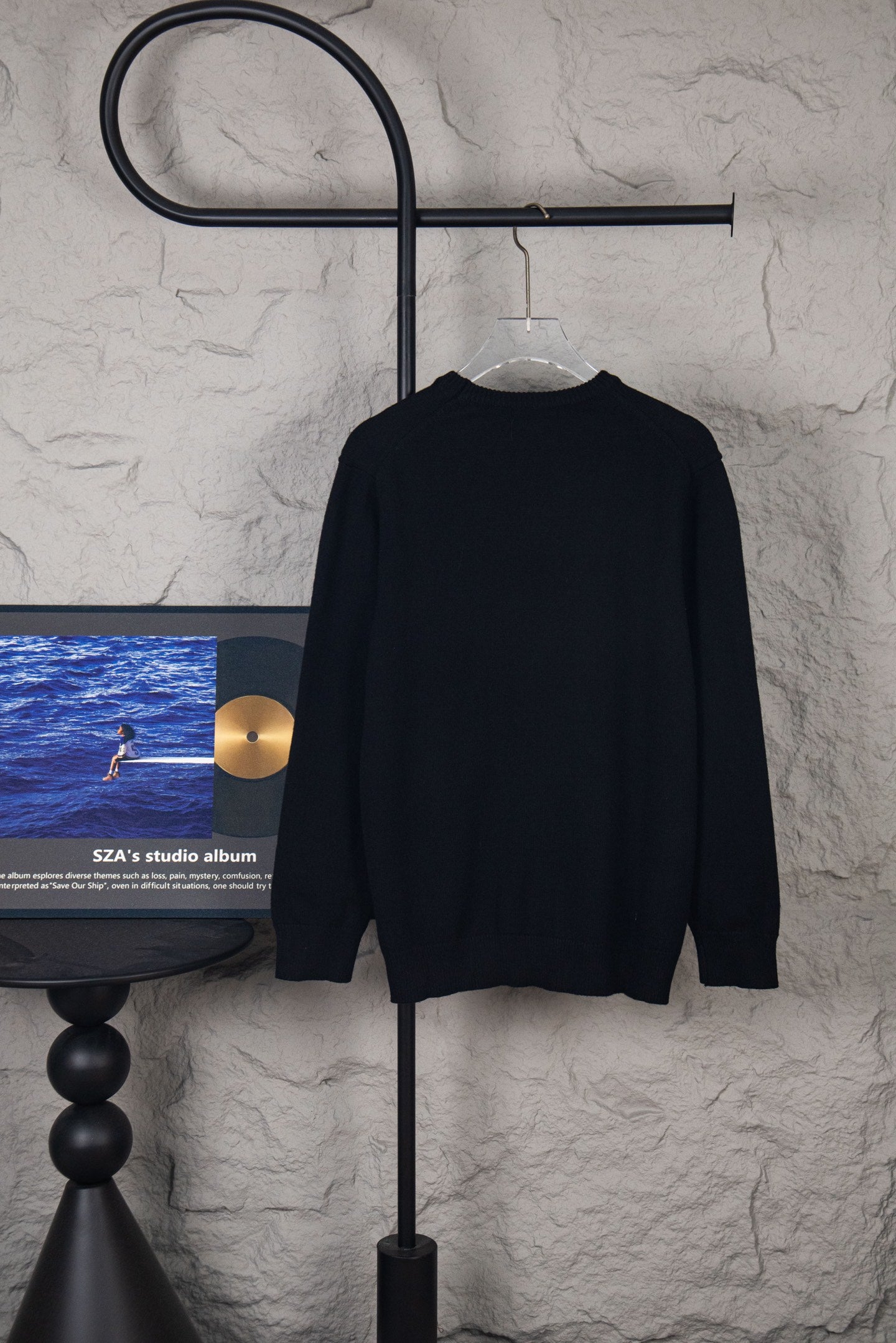 Black long-sleeve sweater on hanger, back view