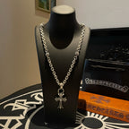 Silver cross pendant necklace with curb-style chain on a display bust