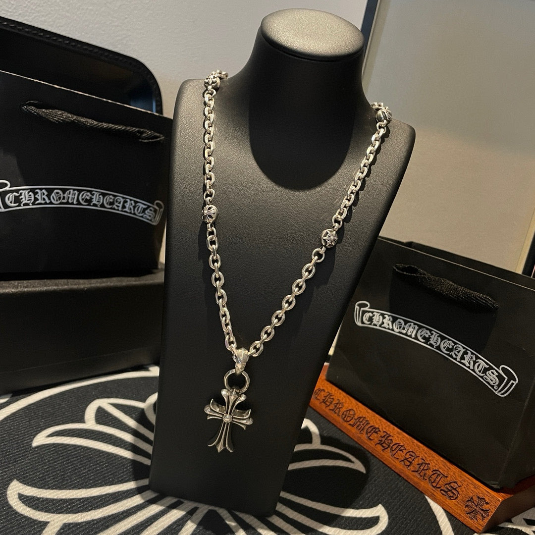 Silver cross pendant necklace with curb chain on a black display bust