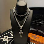 Silver cross pendant necklace with layered curb chain on display bust