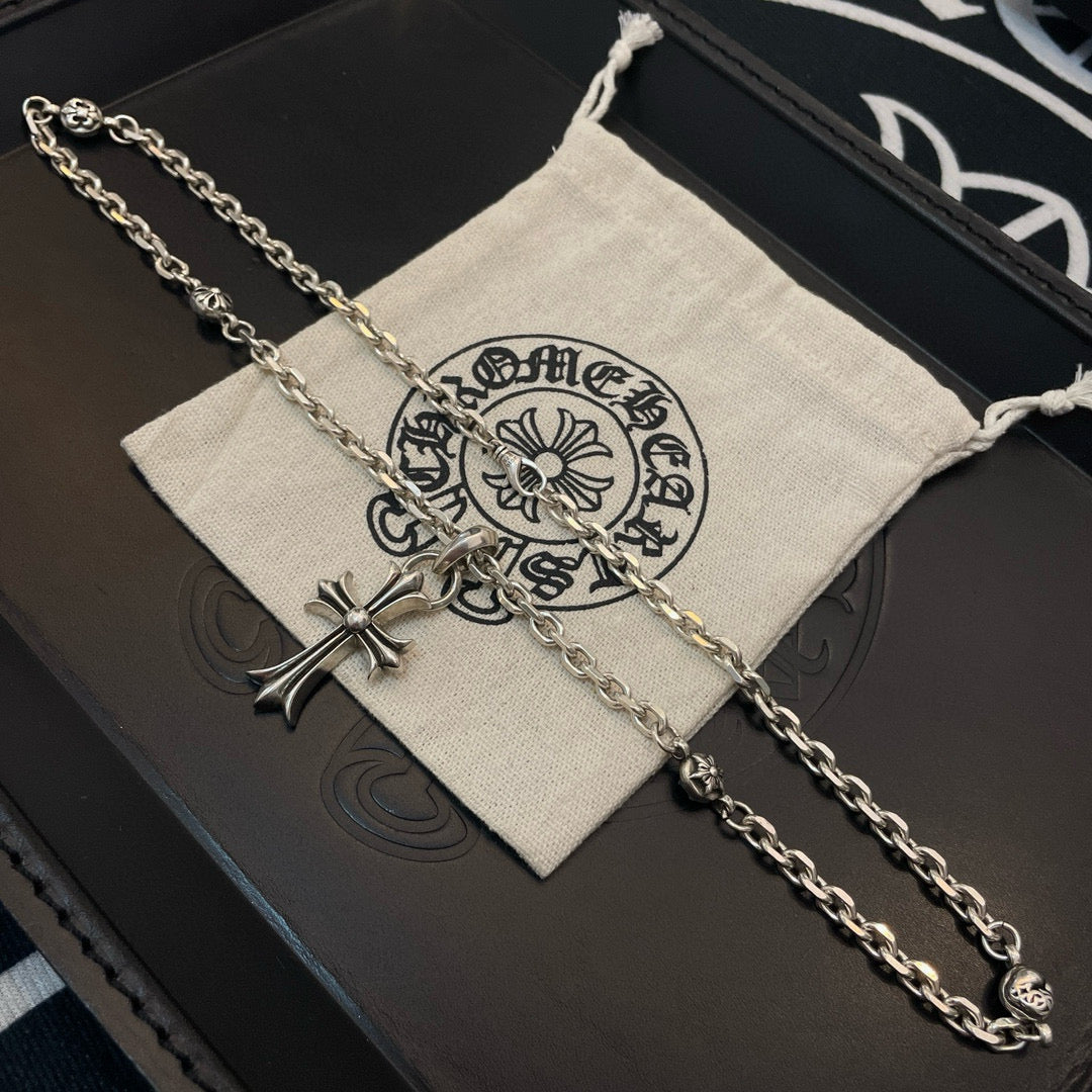 Silver cross pendant necklace with curb chain on folded fabric pouch