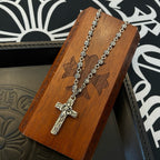 Silver-tone cross pendant necklace on wooden display card