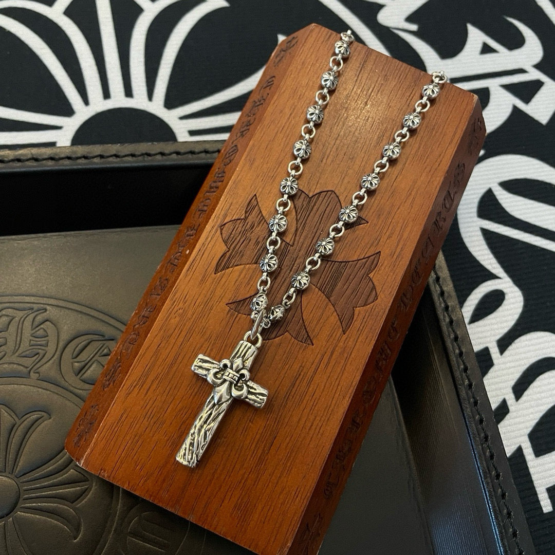 Silver-tone cross pendant necklace on wooden display card