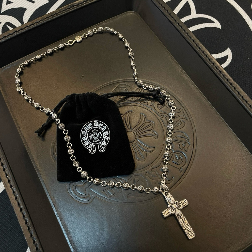Silver-tone cross pendant necklace on embossed tray with black velvet pouch