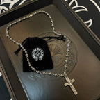 Silver-tone cross pendant necklace on embossed tray with black velvet pouch