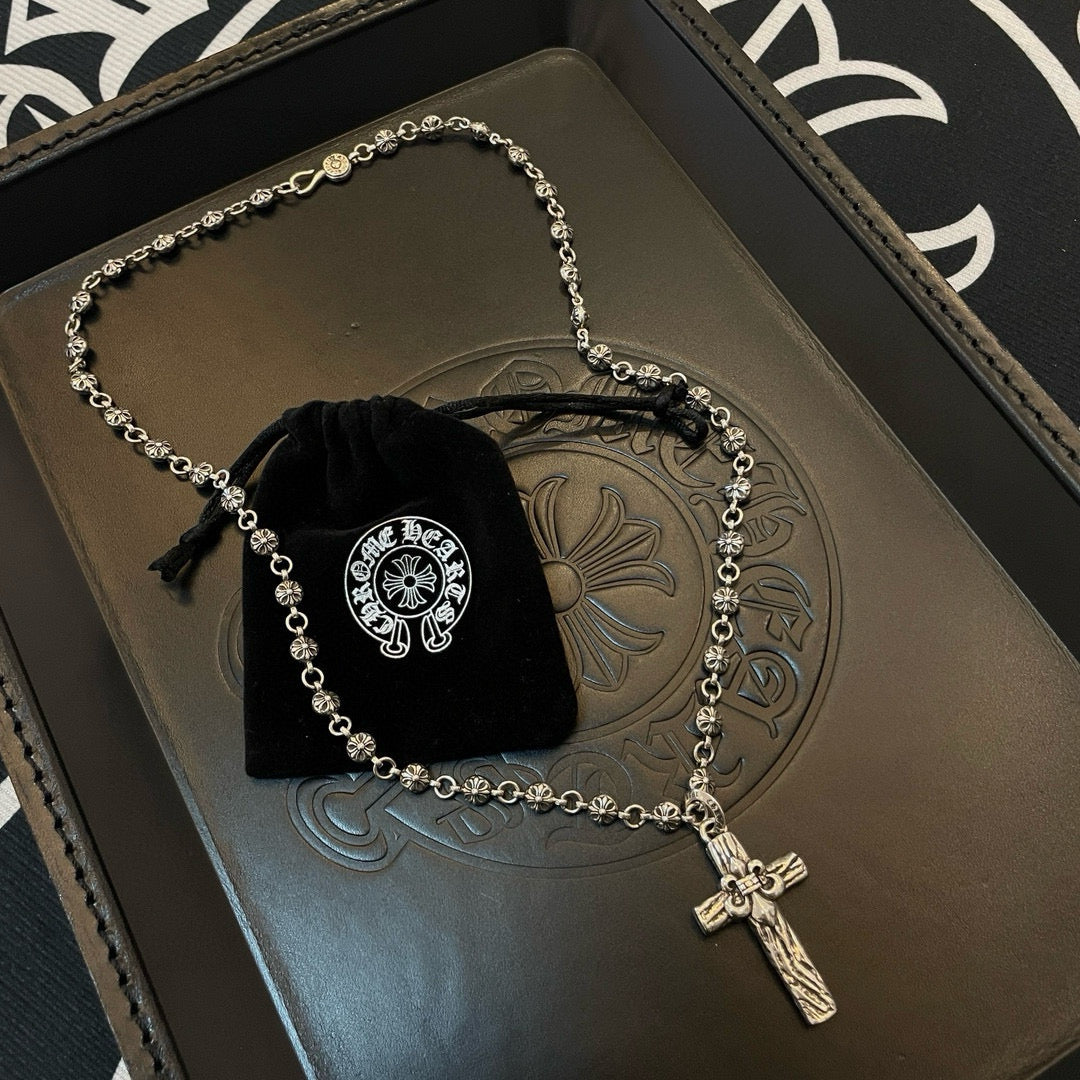 Silver-tone cross pendant necklace on embossed tray with black velvet pouch