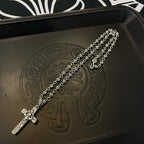 Silver-tone cross pendant necklace draped on embossed leather tray