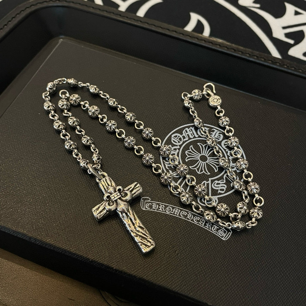 Silver-tone cross pendant necklace on leather tray with embossed emblem