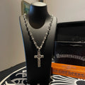 Silver-tone cross pendant necklace with bead chain on black display bust
