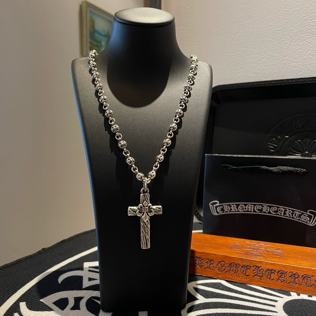Silver-tone cross pendant necklace with bead chain on black display bust