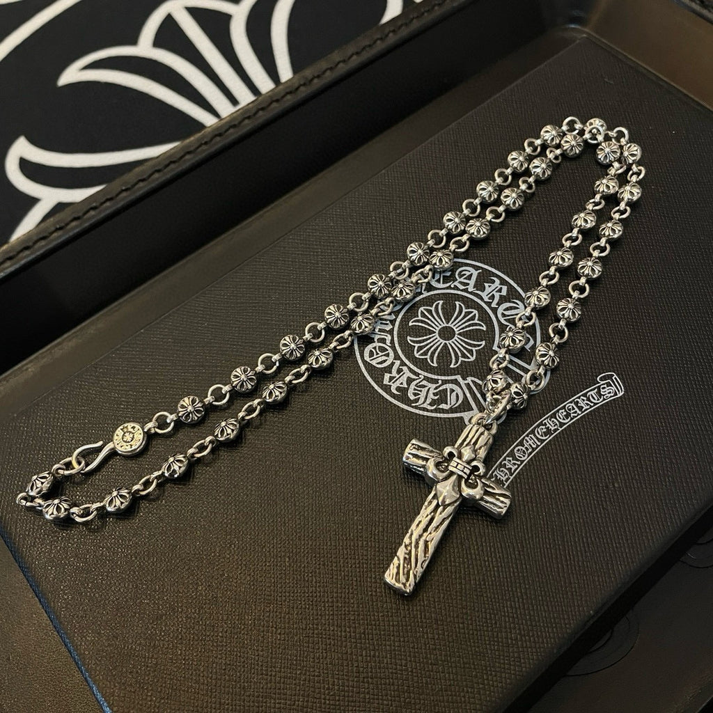 Silver-tone cross pendant necklace on leather tray with circular emblem