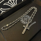Silver-tone cross pendant necklace on leather tray with circular emblem