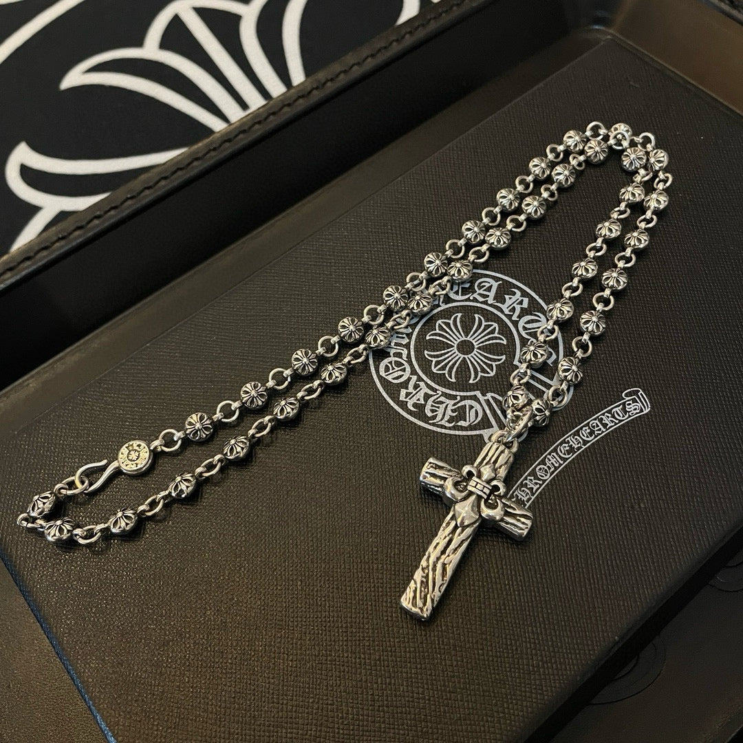 Silver-tone cross pendant necklace on leather tray with circular emblem