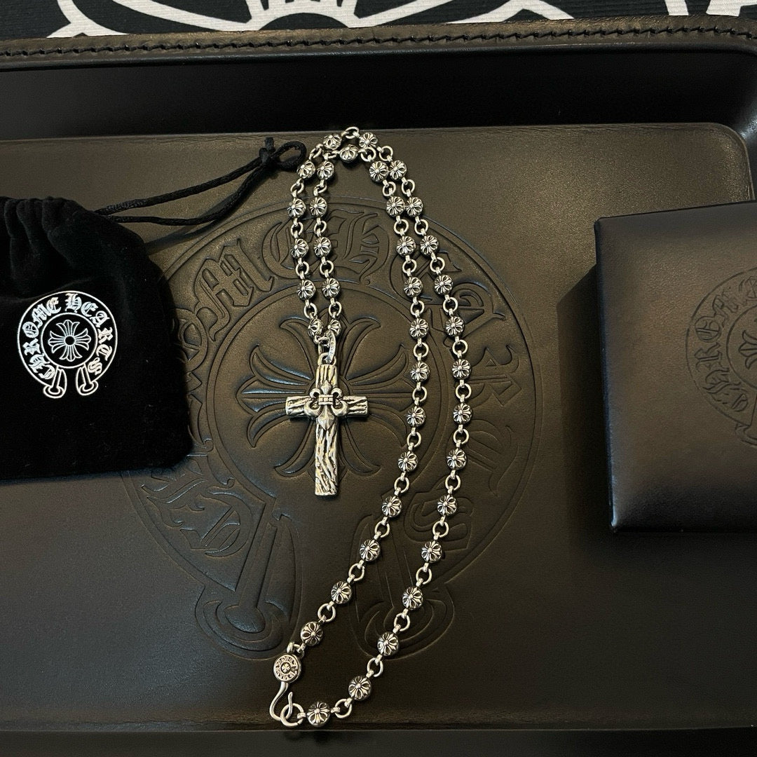 Silver-tone cross pendant necklace on embossed leather tray with velvet pouch