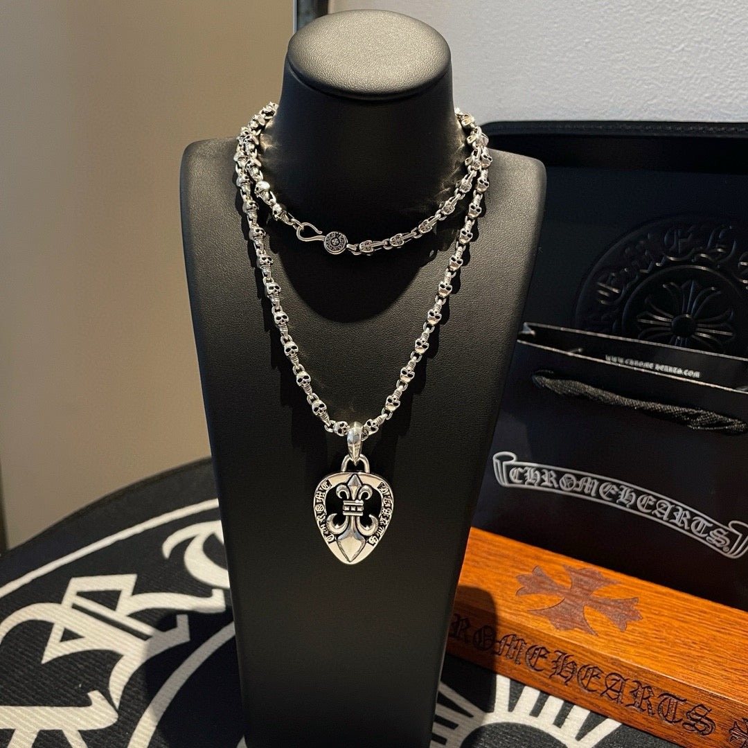 Heart pendant chain necklace with layered silver-tone links on black bust stand