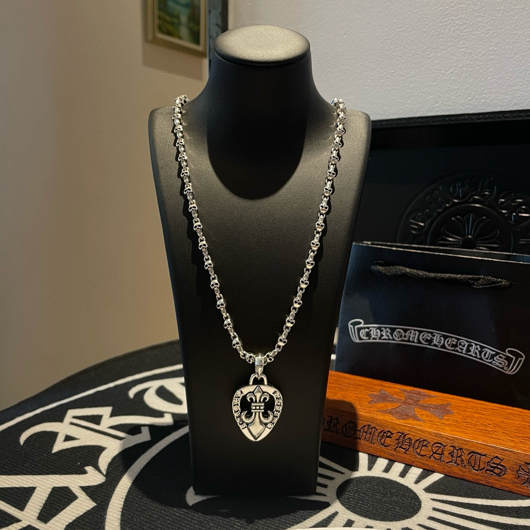Heart pendant chain necklace with silver-tone links on black display bust