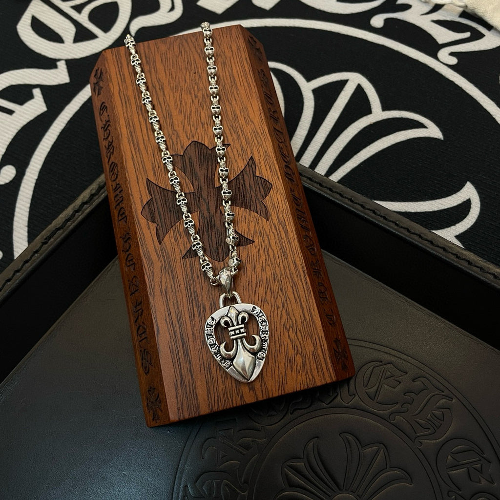 Heart pendant charm necklace with silver-tone chain resting on wooden display block