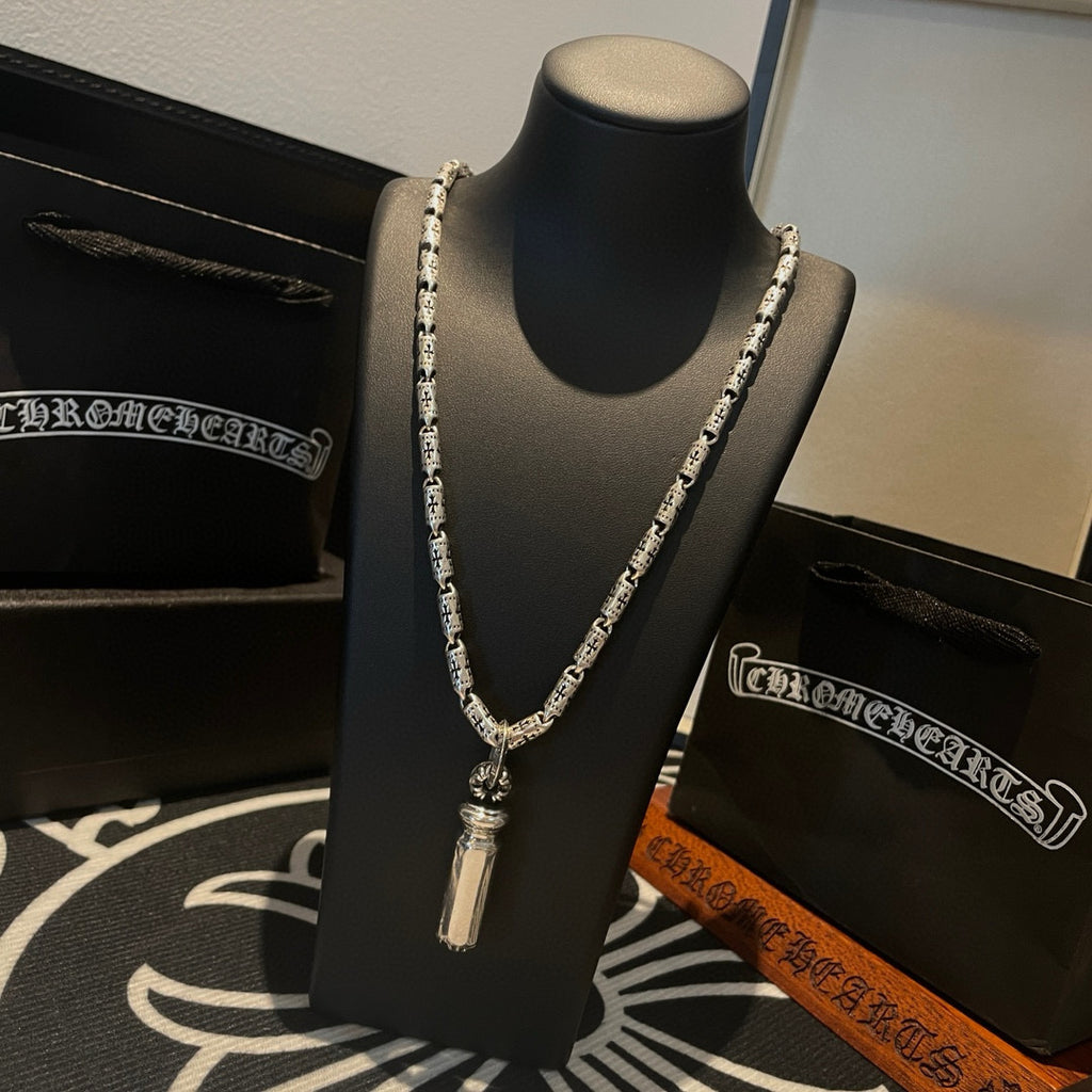 Silver-toned charm necklace with cylindrical pendant and repeating chain links