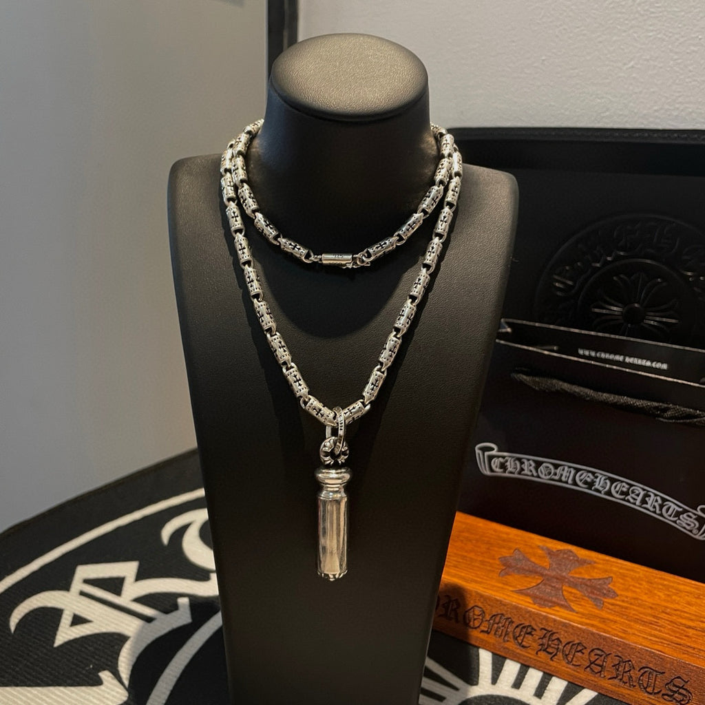 Silver-toned charm necklace with central drop pendant on a black mannequin stand