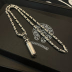Silver-toned charm necklace set on a dark jewelry box with printed emblem