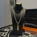 Silver-toned charm necklace with short pendant on a black display stand