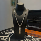 Silver-toned charm necklace with short pendant on a black display stand