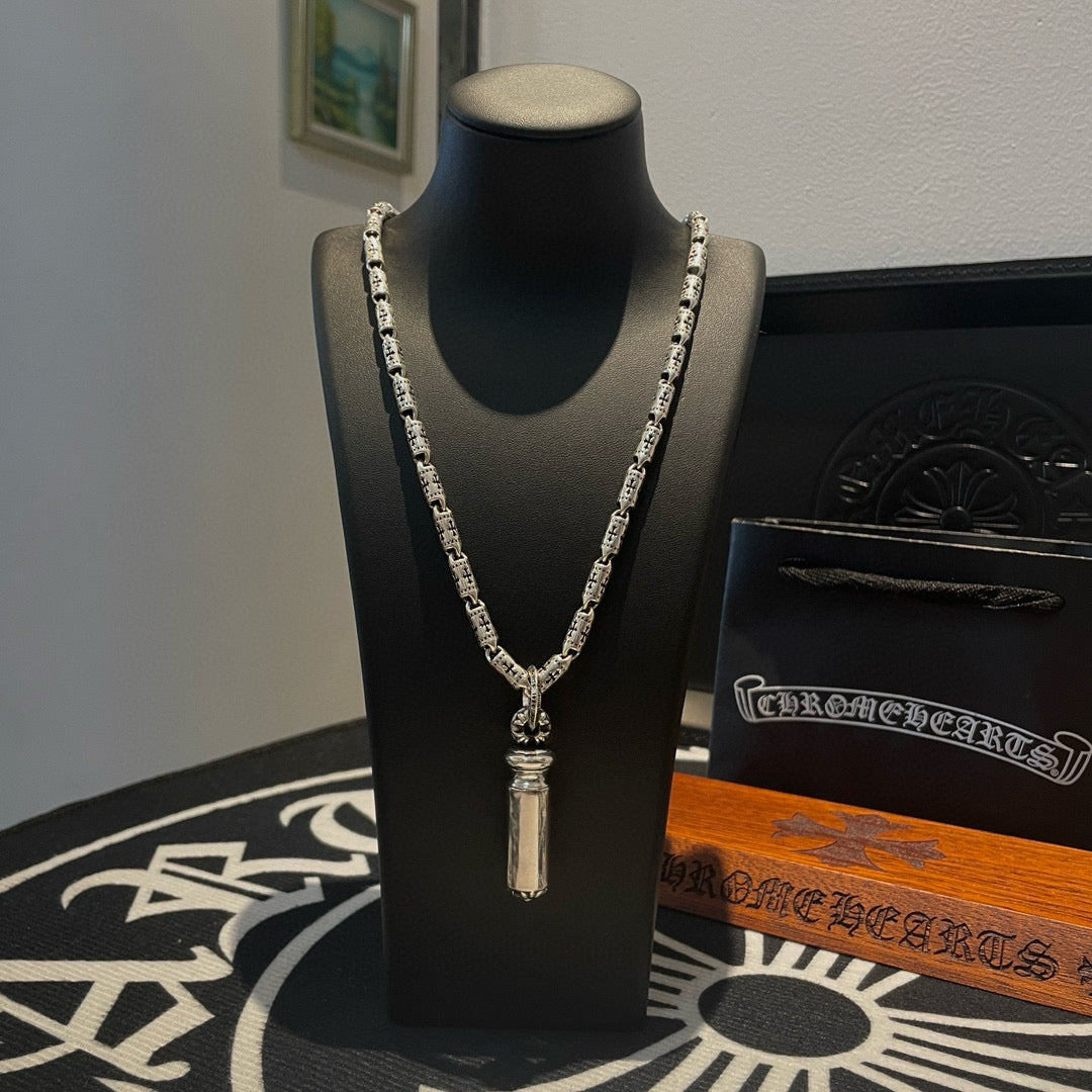 Silver-toned charm necklace with short pendant on a black display stand