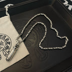 Silver-toned charm necklace with cylinder pendant, coiled on a black box
