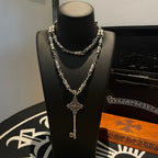 Key pendant necklace with silver chain and fleur-shaped cross charm on bust display