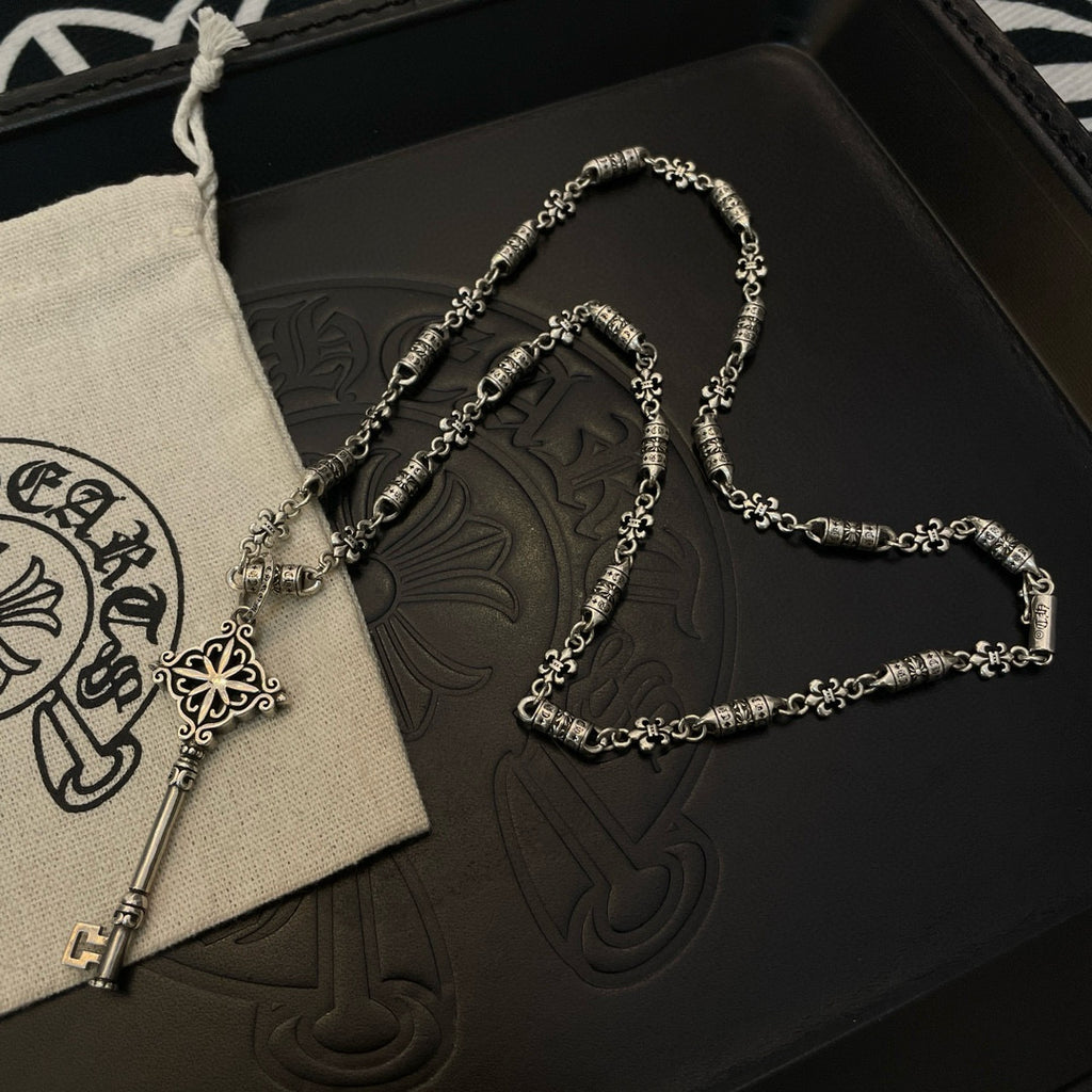 Key pendant necklace and chain on black box with beige pouch and white drawstring