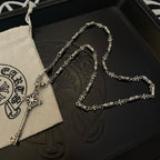 Key pendant necklace and chain on black box with beige pouch and white drawstring