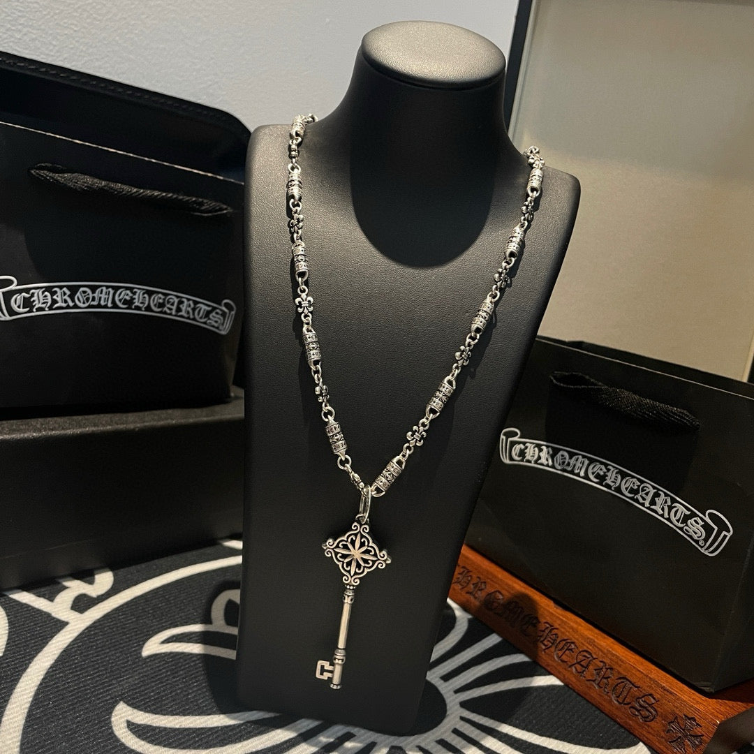 Key pendant necklace on bust display with matching chain and fleur cross charm