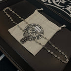 Silver beaded chain necklace with pendants resting on beige pouch
