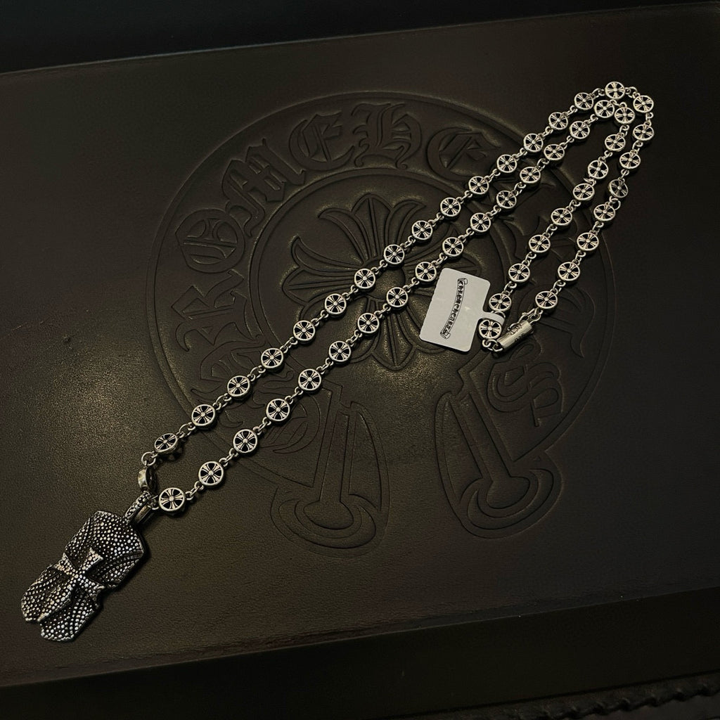 Silver beaded chain necklace laid on dark box with engraved emblem