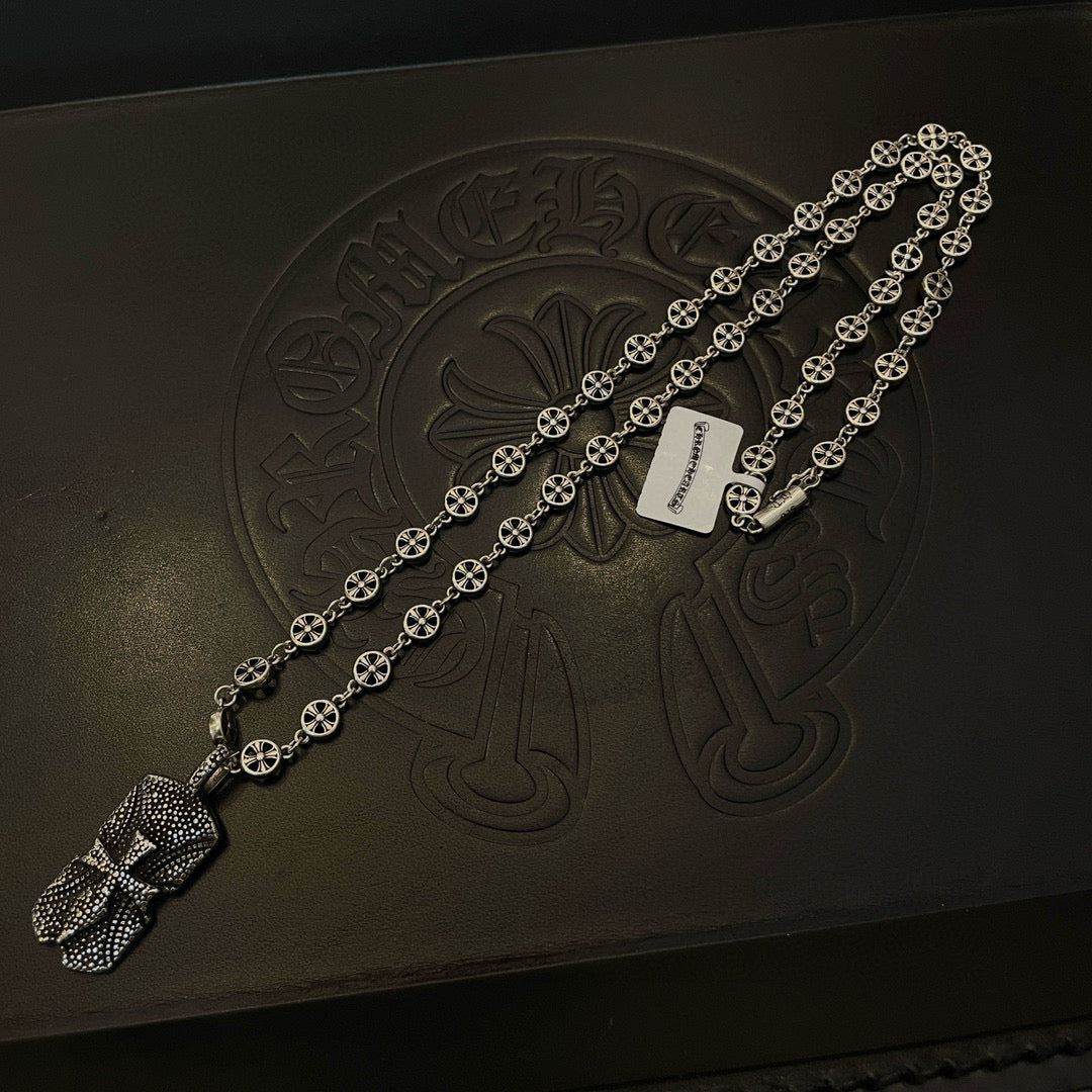 Silver beaded chain necklace laid on dark box with engraved emblem