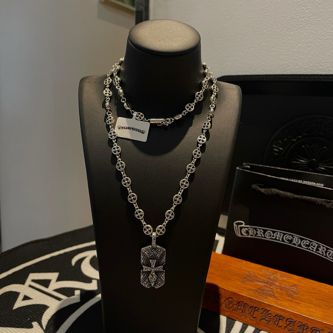 Silver beaded chain necklace with two pendants on black display bust