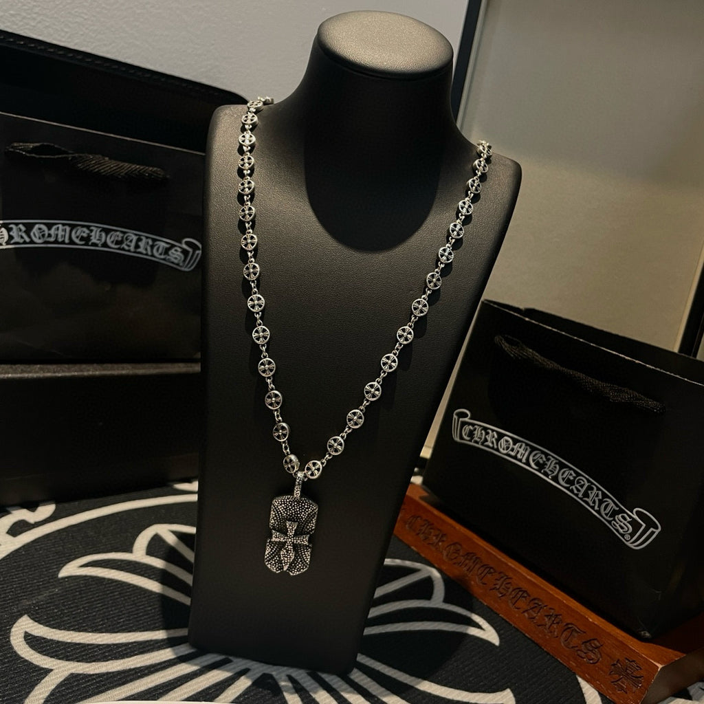 Silver beaded chain necklace with heart-like pendant on black display bust