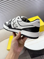 White and black lace-up sneaker held near the heel with visible side logo