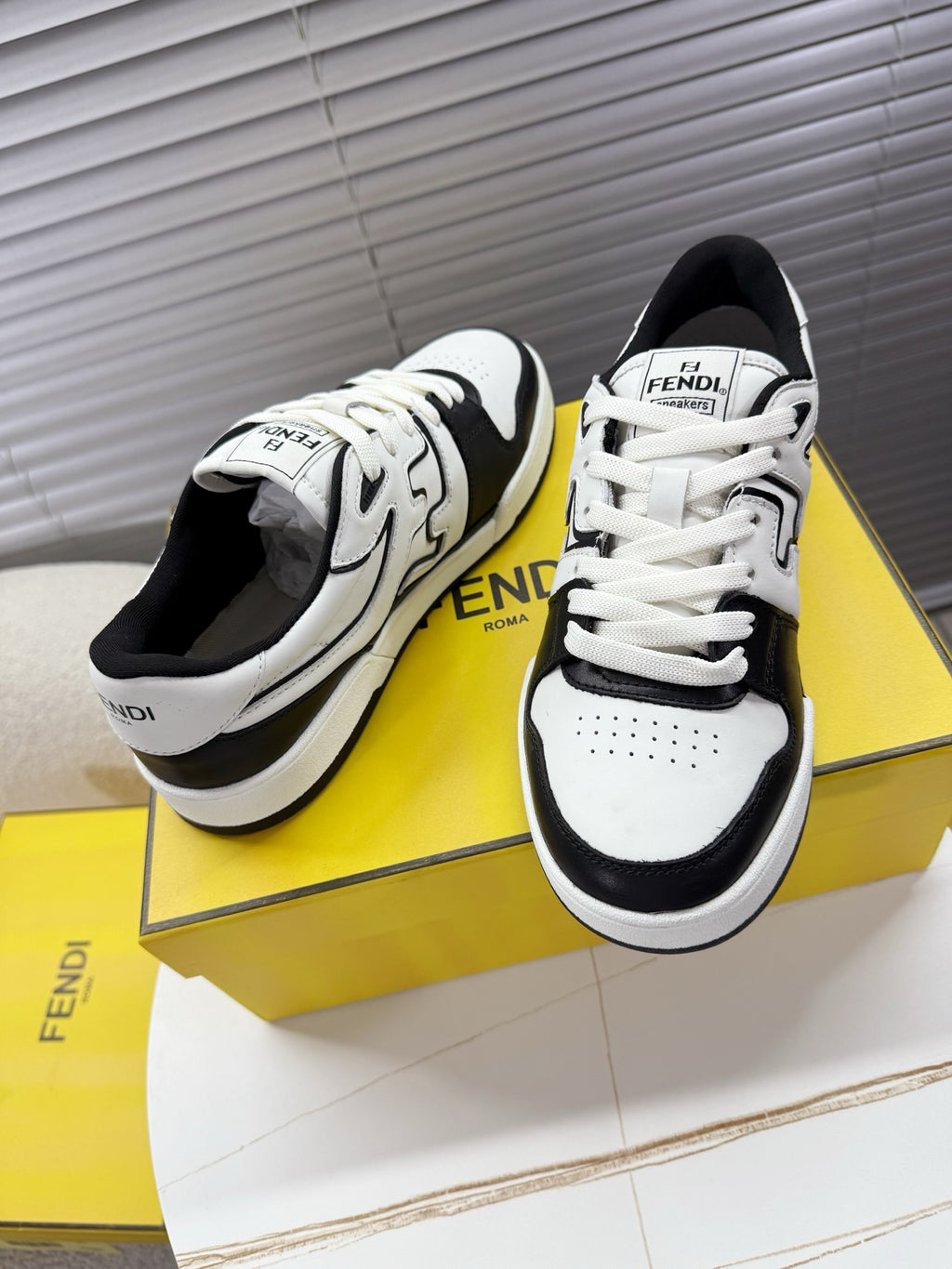 White and black lace-up low-top sneakers with FENDI logo, angled pair view