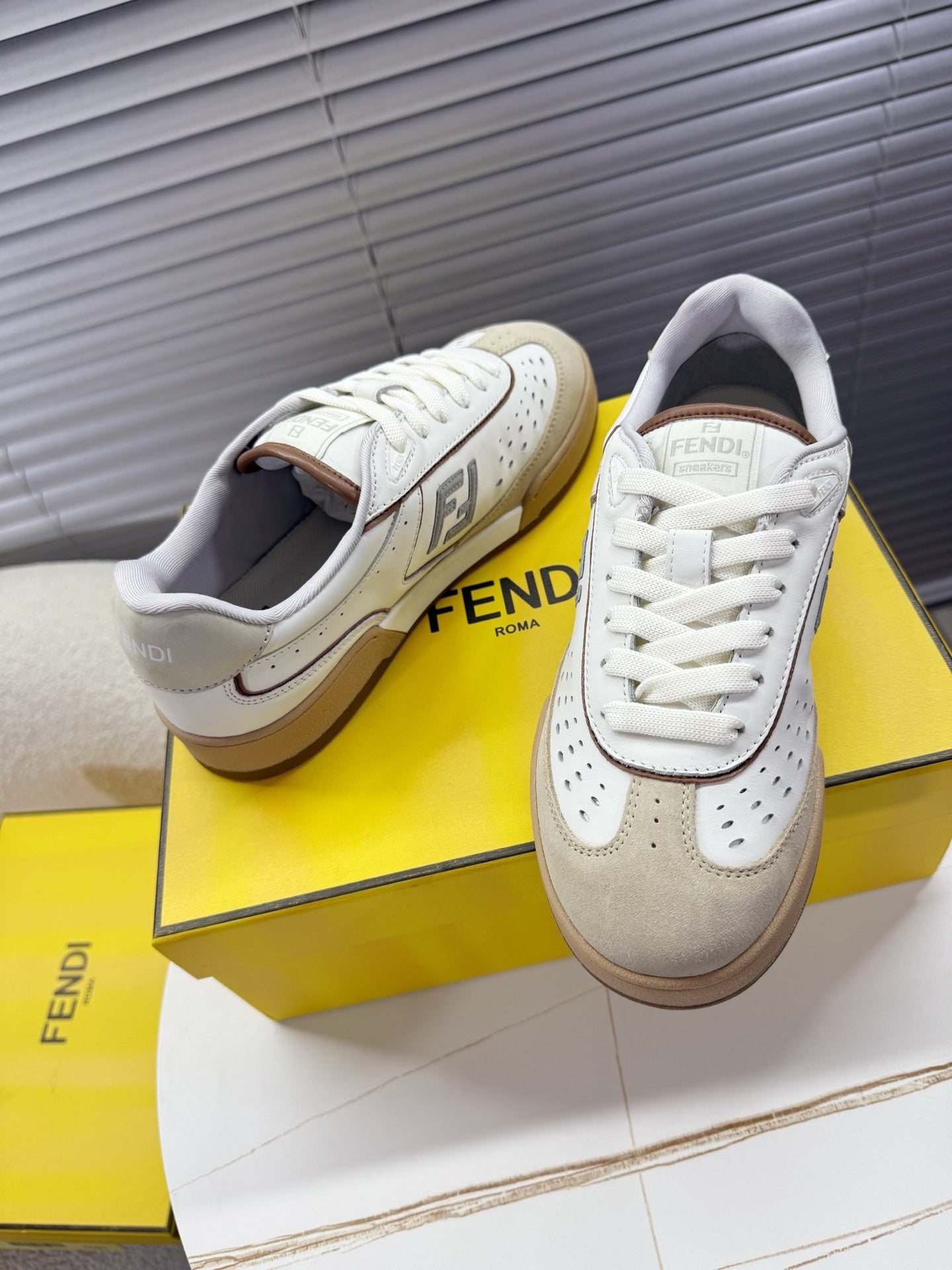 Fendi unisex sneakers pair with white uppers, beige lining, and lace-up design.